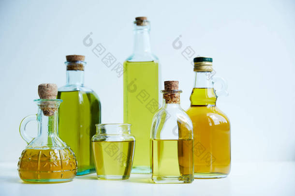不同瓶的芳香橄榄油和罐子在白色背景