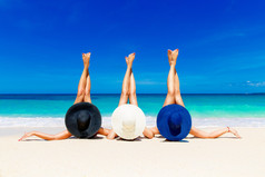 三名年轻女子在草帽躺在一个热带的海滩，延伸