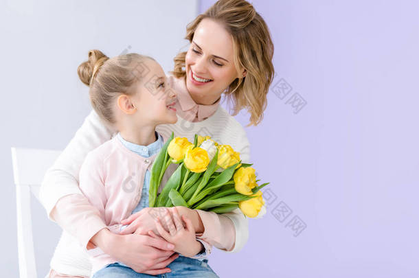 可爱的孩子拥抱母亲与郁金香花束在3月8日
