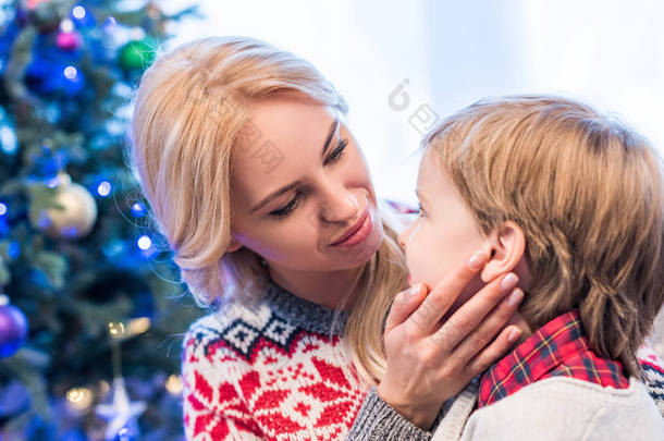 美丽的年轻母亲看可爱的小儿子在圣诞节时间