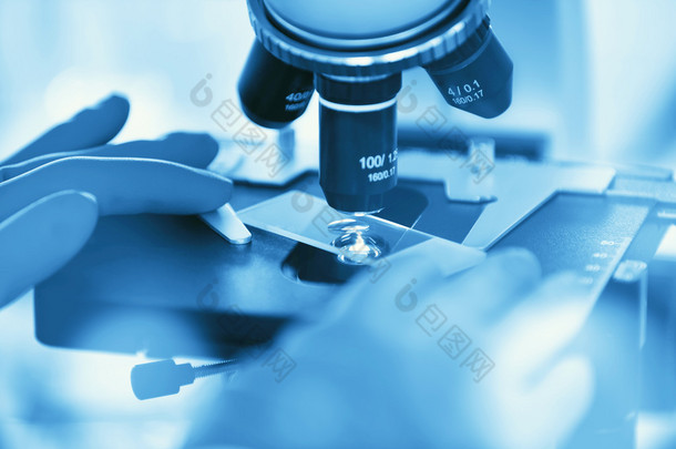 用显微镜检查样品和液体的科学家手的特写镜头.