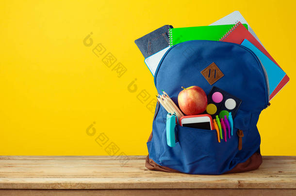 带笔记本、智能电话和铅笔的书包背包, 上面有黄色背景.