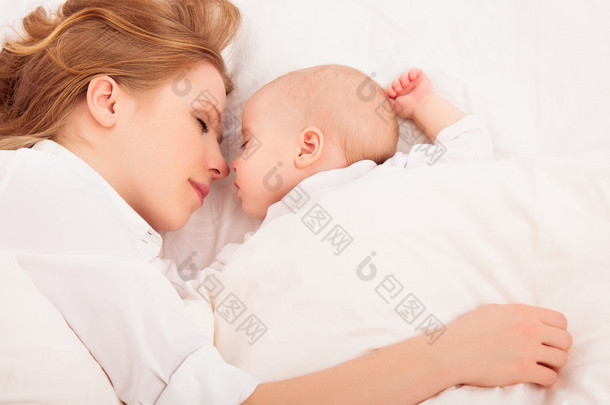 母亲拥抱在一起睡在<strong>床上</strong>的婴儿