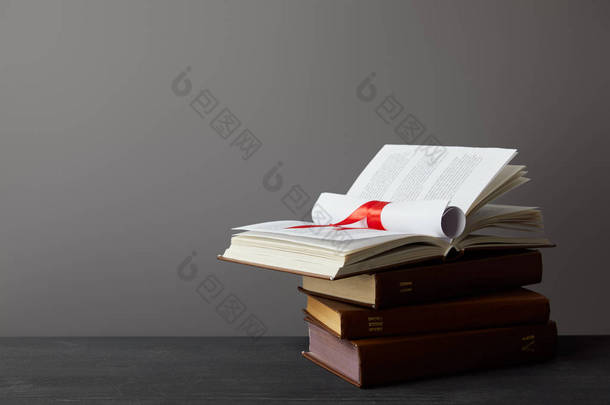 书和文凭与<strong>红色</strong>丝带在黑暗的表面在灰色