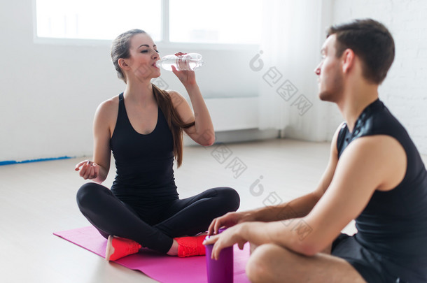 体育连接人朋友放松锻炼女孩饮用水和男人身边的年轻夫妇在查看后体育服装坐说话交谈.