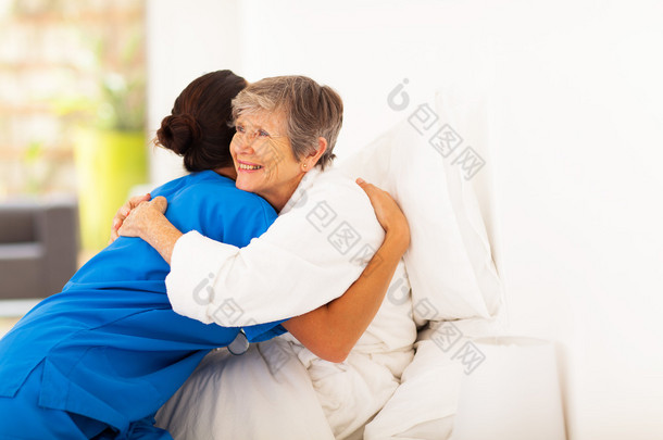 快乐老人的女人在床上拥抱照料者