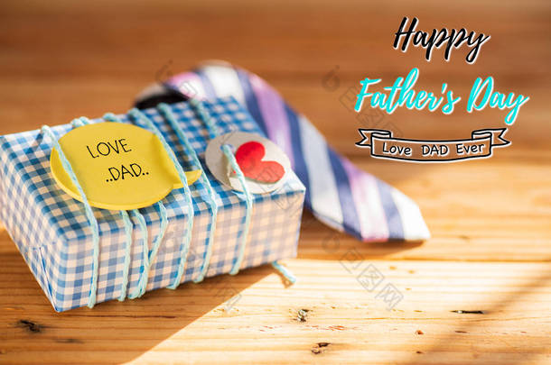 快乐的父亲日概念。彩色领带和礼物盒与爱爸爸标签在木桌背景.