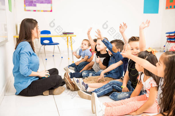 一组学龄前学生举手和尝试参加学校的个人资料视图