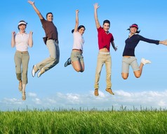跳跃的年轻快乐集团在草地上