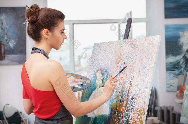 一个年轻的女艺术家在她的艺术工作室工作时的后视镜照片