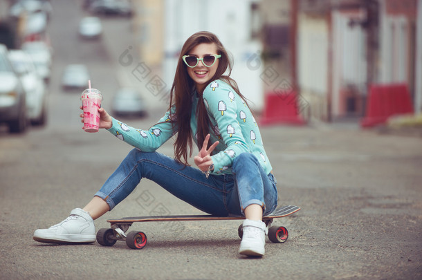 年轻漂亮的女人，和一个滑板，时尚的生活方式，在日落时的合影