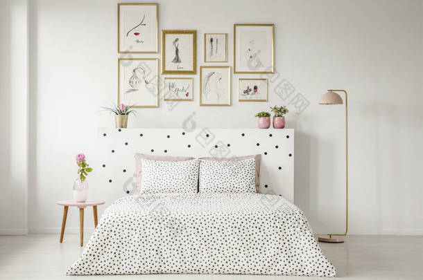 床头床上的花纹床上用品桌上有粉红色花的妇女卧室内饰