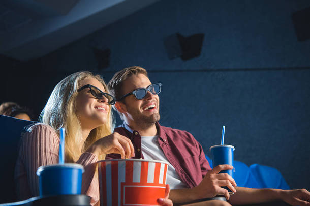 欢快的情侣在3d 眼镜与爆米花一起看电影在电影院