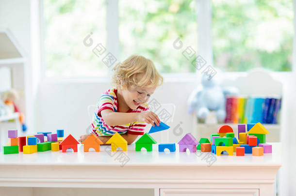 孩子玩<strong>彩色</strong>玩具块。小男孩用方块玩具建造塔楼。幼儿教育和创意玩具和游戏。婴儿在白色的卧室里用彩虹砖。在家的儿童.
