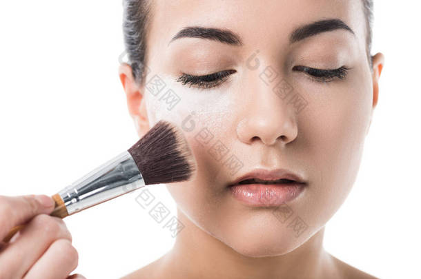 visagiste 的裁剪图像在白色的面部粉末上做化妆的年轻妇女
