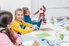 孩子们在笔记本上写字, 在桌上用笔记本电脑, 在阀杆类用红色机器人
