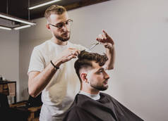 在理发店理发的年轻人. 理发师负责理发和修剪胡子. 概念理发店.
