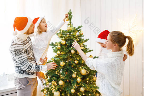 家庭母亲父亲和孩子装饰一棵圣诞树在
