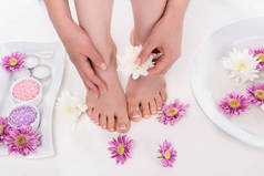 用鲜花, 蜡烛, 五颜六色的海盐和沐浴指甲在美容院拍摄的赤脚妇女 