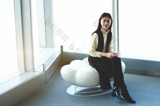 Young Japanese businesswoman with mobile phone in hands is waiting international partners in airport