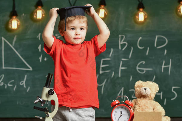 幼儿园毕业的概念。第一个对学习、教育感兴趣的人。孩子, 学生在微笑的脸上与 mortarboard。孩子的研究生帽准备上学, 黑板上的<strong>背景</strong>.