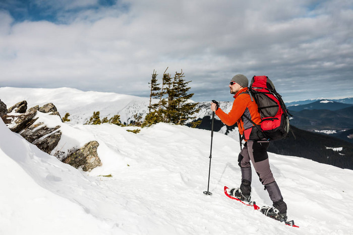 一个人爬上山顶登山运动员在雪地鞋背着一个