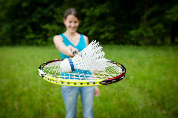 漂亮打羽毛球在城市公园中的女人