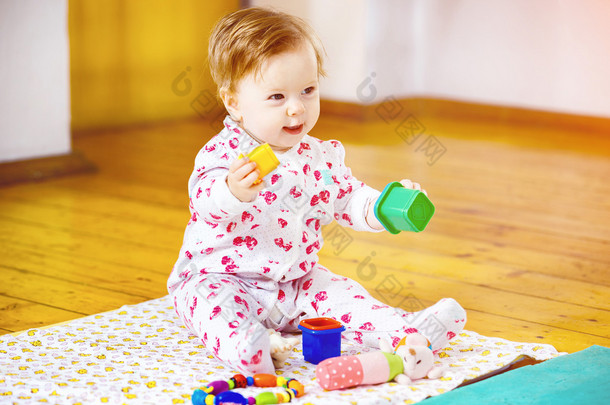 可爱的婴儿女孩玩玩具积木在地板背景的肖像.