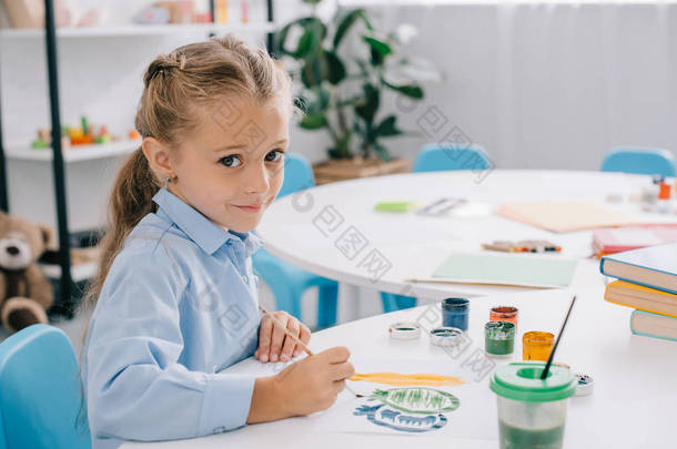 可爱的孩子坐在桌子上, <strong>油</strong>漆和<strong>油漆刷</strong>的侧面视图 