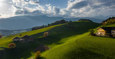 意大利阿尔卑斯山的绿地，高山的绿坡，博尔扎诺，山谷上空的巨大云彩，房屋的屋顶，背景上的白云石，在云彩中闪耀的空中美景