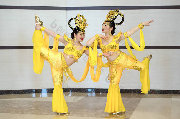 在黄色的传统中国舞台服装的两个漂亮的女孩会场