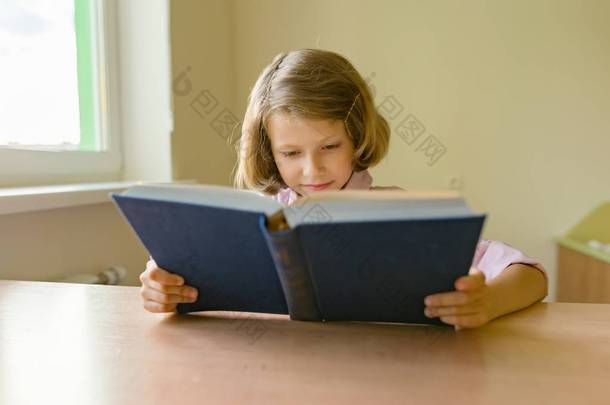 小女生坐在课桌旁看书。学校、教育、知识和儿童