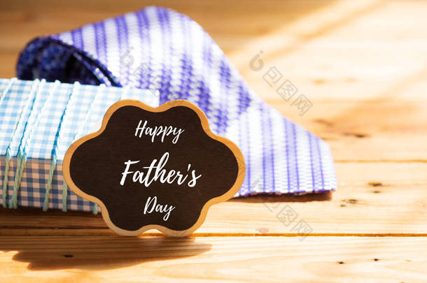 快乐的父亲日概念。紫色领带和礼品盒与快乐父亲节标记在木桌背景.