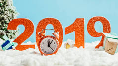大红色2019年数字与老式闹钟和礼物在雪在蓝色背景, 新年概念
