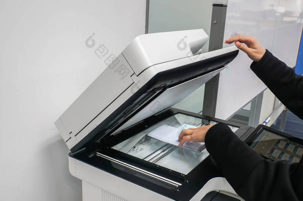 关闭女实业家将文件放在打印机上, 以便在办公室进行扫描和复制