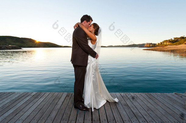 新婚夫妇在日落时一个突堤码头上接吻