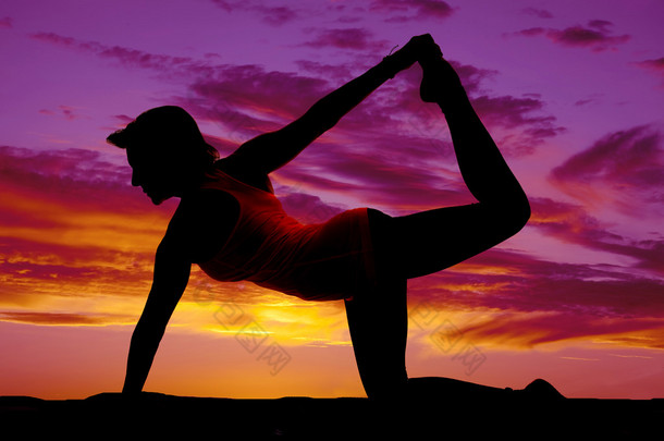 女人做瑜伽健身术对膝关节举腿的剪影