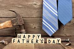 快乐的父亲节在背景下的工具和领带的木制积木反对质朴的木材