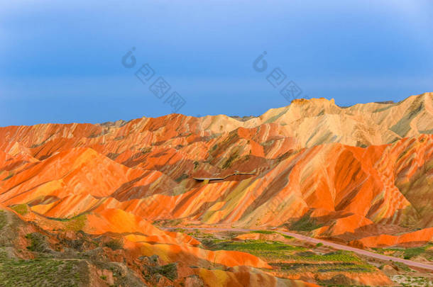 彩虹山迷人的风景和夕阳西下的蓝天背景.中国甘肃张业丹霞国家地质公园。五彩缤纷的风景，彩虹的山丘，不同寻常的彩色岩石，砂岩的侵蚀