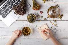 各种茶叶的头顶景色。用各式各样的草药调味, 一个苹果, 玫瑰与茶壶和茶杯在乡间餐桌上