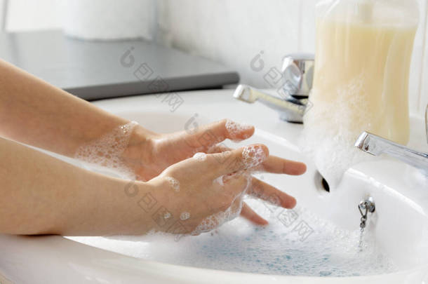 小孩的手靠得很近，把他的手放在浴室的<strong>水</strong>槽上洗了.