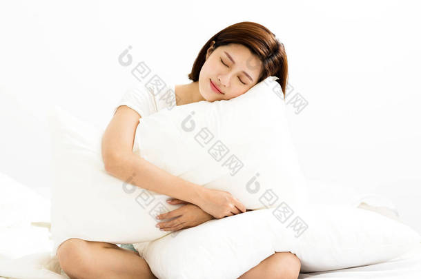 年轻的<strong>女人</strong>在床上的房间里抱着枕头
