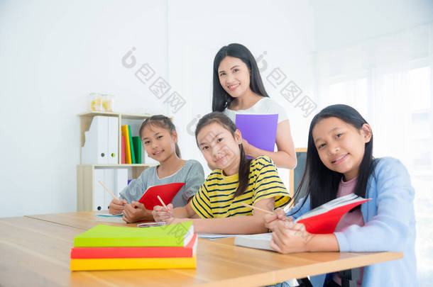三个亚洲学生在教室里坐着看书 