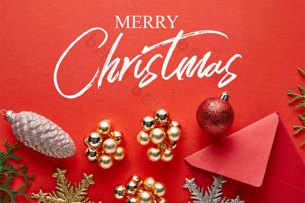 明亮的圣诞装饰、信封和红色背景的thuja的顶部视图，附有圣诞快乐的插图