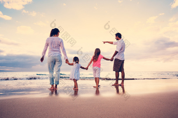 幸福年轻的家庭，在日落时分的海滩上