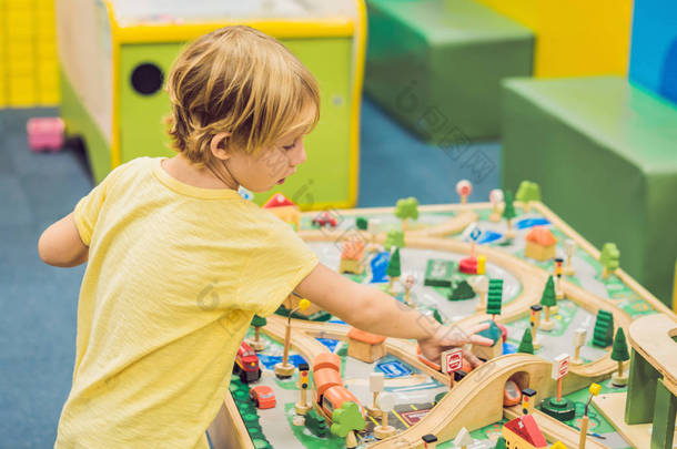 孩子玩木制玩具, 在家里或托儿所建造玩具铁路。蹒跚学步的男孩玩起重机, 火车和汽车。学前和幼儿园儿童的教育玩具。软垫<strong>家具</strong>, 椅子袋.