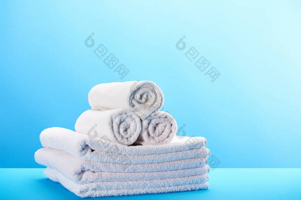 轧制和堆叠干净的白色毛巾在蓝色 
