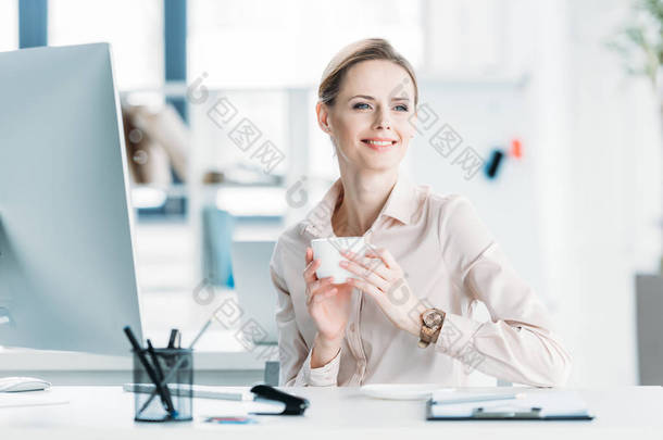 微笑的女商人在办公室喝咖啡