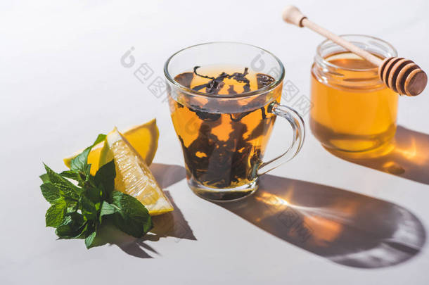 健康红茶与蜂蜜, 柠檬和薄荷在杯子在白色桌上
