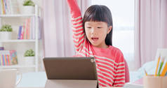 亚洲的女学生们用平板电脑快乐地在网上上课，她举起胳膊回答老师们的问题
